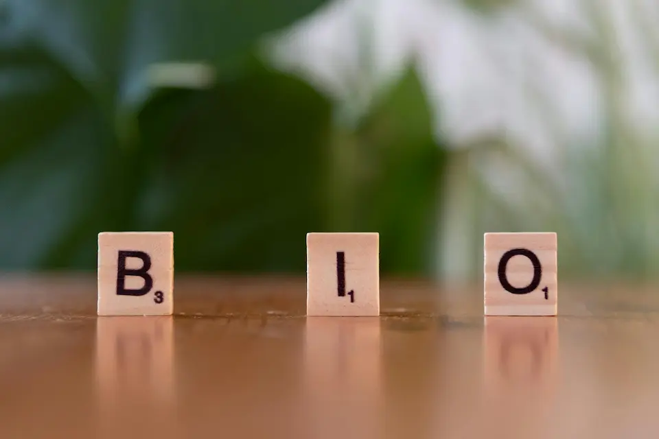 Scrabble tiles spell out 'BIO' on a table, set against a vibrant green background.